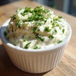 A close-up of creamy, homemade tartar sauce recipe topped generously with fresh chopped parsley, served in a white ramekin.