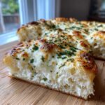 A thick slice of amazing white pizza showing a fluffy interior, melted cheese topping, and fresh parsley.