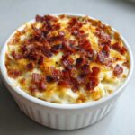 Close-up of creamy jalapeño popper dip topped generously with crispy bacon bits in a white ramekin.