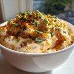 Creamy, rich caramelized onion dip topped with sweet onions and fresh chives in a white bowl.