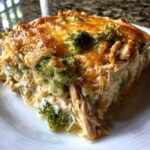 A generous slice of creamy Chicken Divan casserole featuring shredded chicken, broccoli florets, and a golden melted cheese topping.