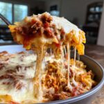 A spoonful of cheesy skillet lasagna showing long, stretchy mozzarella pulls over rich meat sauce.