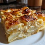 A close-up of a thick, cheesy slice of scalloped potatoes with a golden-brown, bubbly top crust.