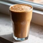 A tall, frosty glass filled with a thick, brown Coffee Smoothie, condensation visible on the exterior.