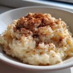 Close-up of creamy rice pudding recipe served in a white bowl, generously dusted with ground cinnamon.