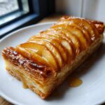 A rectangular slice of easy apple tart with overlapping glazed apple slices on flaky pastry, dusted with powdered sugar.