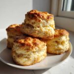 A stack of four tall, fluffy, golden brown scones showing excellent rise and flaky layers.