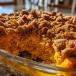 Close-up of a scooped portion of fluffy sweet potato souffle topped with a rich, brown sugar crumb topping.