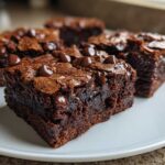 Close-up of fudgy black bean brownies squares topped with melted chocolate chips on a white plate.