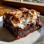 A close-up of a fudgy hot chocolate brownie topped with toasted, golden-brown marshmallow.