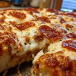 Close-up of a baked pepperoni pizza dip showing melted, stringy cheese and crispy pepperoni slices.