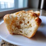 Close-up of a halved homemade english muffin showing its airy, porous interior crumb structure.