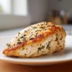 A perfectly cooked, juicy chicken breast seasoned with herbs, showing a golden sear, achieved using the ultimate chicken marinade.