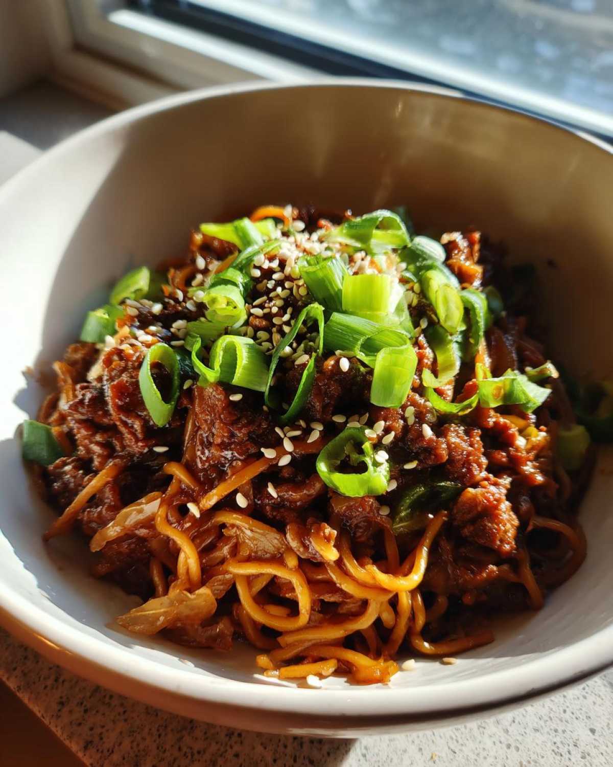 A close-up of a serving of keto egg roll in a bowl, topped generously with sliced green onions and sesame seeds.