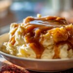 Close-up of fluffy mashed potatoes generously topped with rich, brown chicken gravy.