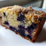 Close-up of a moist slice of blueberry banana bread topped with a brown sugar streusel.