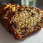 Close-up of moist chocolate chip banana bread, showing the soft crumb and rich brown crust.