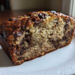 Close-up of a moist slice of greek yogurt banana bread featuring visible chocolate chips throughout the crumb.