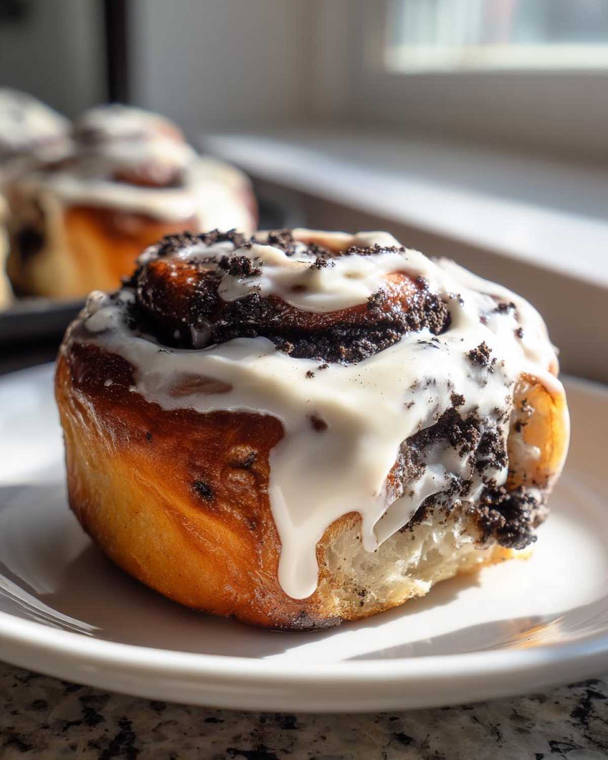 A close-up of one freshly baked oreo cinnamon roll topped with white icing and crushed cookie pieces.