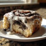 Close-up of a single, gooey oreo cinnamon rolls slice topped with white icing and crushed cookies.