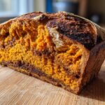 Close-up of the vibrant orange crumb and dark crust of a freshly baked pumpkin sourdough loaf.