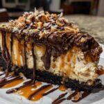 A rich slice of Samoa Cheesecake with a dark crust, drizzled heavily with chocolate and caramel, topped with toasted coconut.