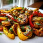 Close-up of perfectly seasoned shrimp fajitas mixed with red and yellow bell peppers and onions, garnished with cilantro.