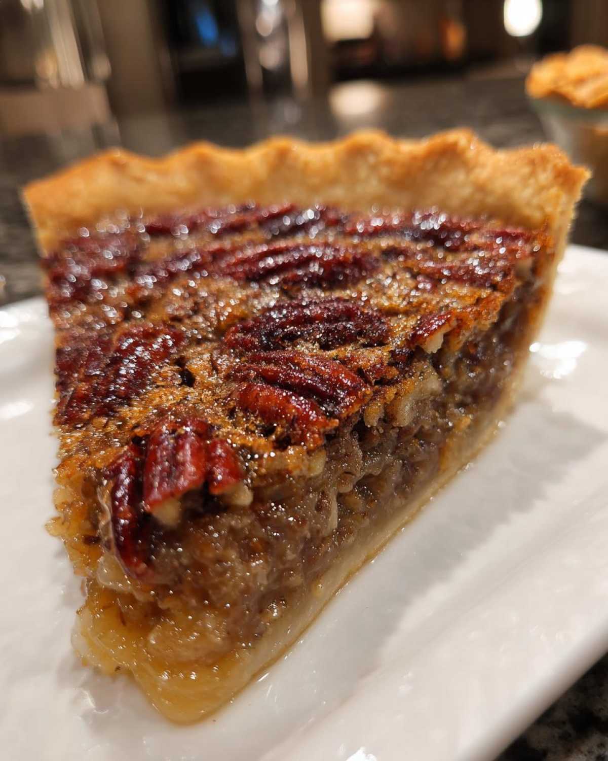 Close-up of a perfectly baked slice of pecan pie showing the caramelized topping and gooey filling.