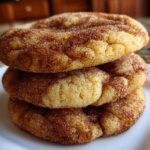 A close-up stack of three soft, chewy snickerdoodles cookies generously coated in cinnamon sugar.