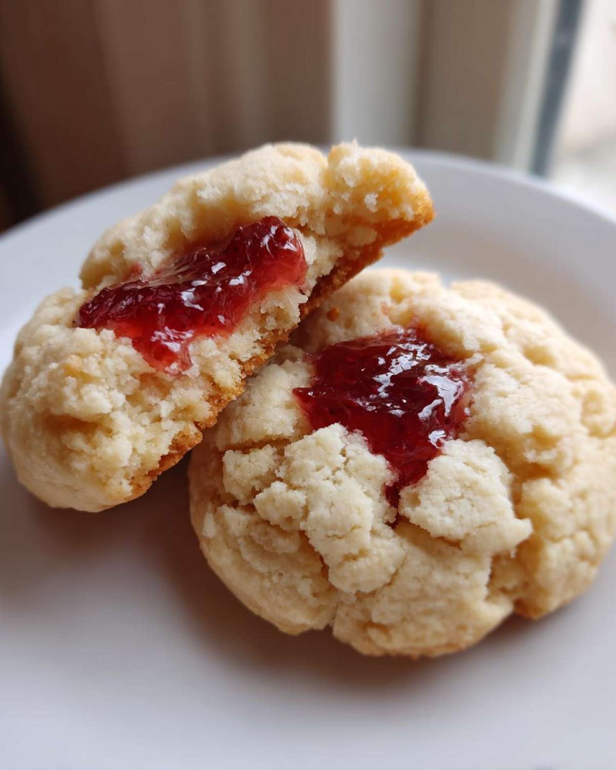 Close-up of two strawberry cheesecake cookies, one broken open showing the jammy center.