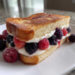A thick slice of golden brown stuffed french toast filled with cream cheese and fresh raspberries and blackberries.