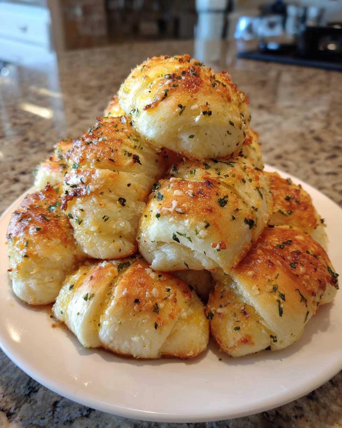 A mound of freshly baked, golden garlic breadsticks seasoned with parsley and Parmesan cheese.
