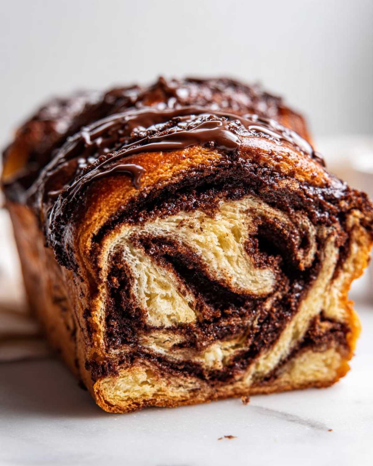 Close-up cross-section of a freshly baked chocolate babka showing rich, dark chocolate swirls in the golden dough.
