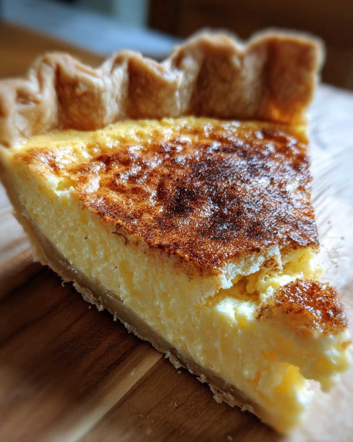 Close-up of a slice of creamy egg custard pie with a golden, cinnamon-dusted top.