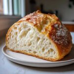 Close-up of a freshly baked french bread loaf, showing the airy, open crumb structure and golden crust.