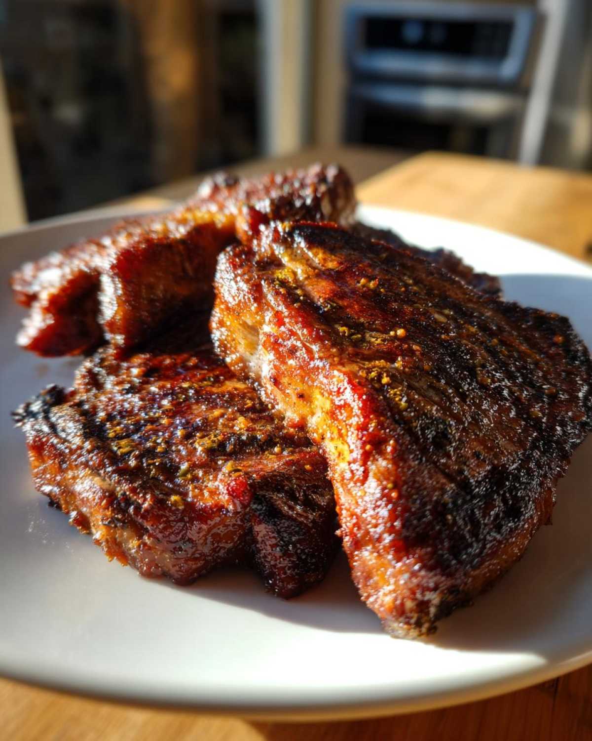 Close-up of three beautifully caramelized and seasoned pork steak cuts resting on a white plate.