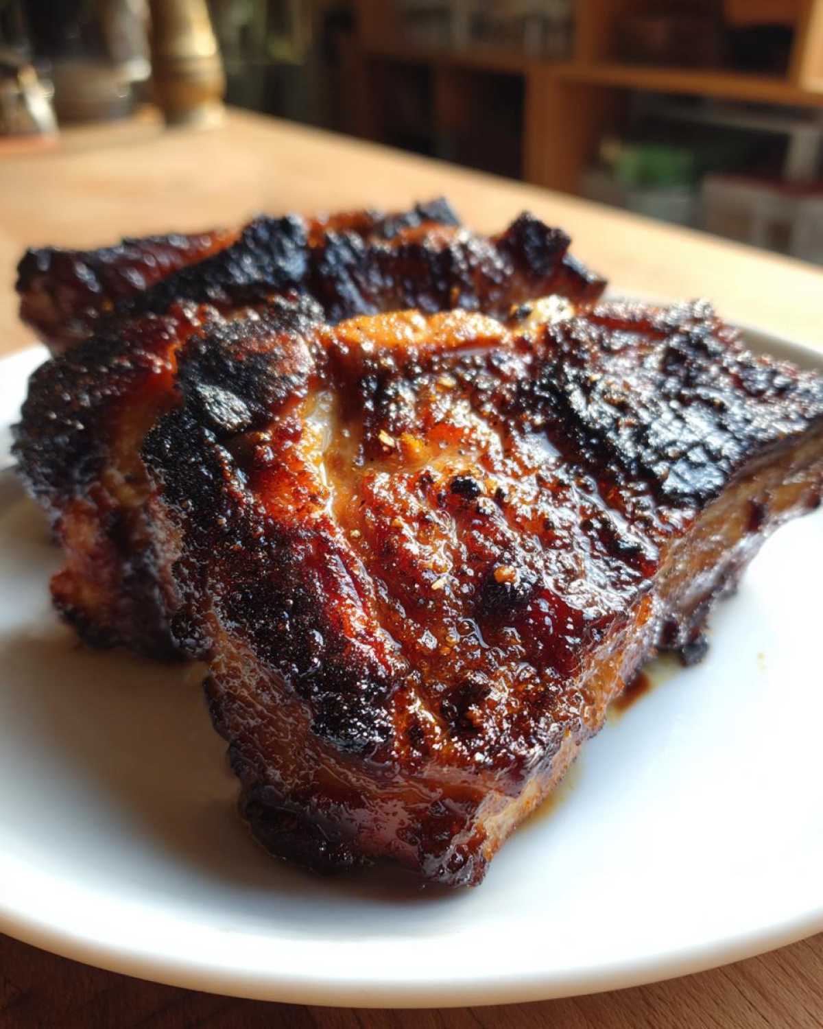 Close-up of perfectly seared, caramelized pork steak with a dark, glossy glaze on a white plate.
