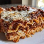 Close-up of a thick, layered slice of homemade lasagna with rich meat sauce and melted cheese topping.