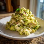 A generous mound of creamy avocado chicken salad mixed with red onion, served on a white plate.