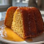 Close-up of a slice of moist Bacardi rum cake drizzled with golden rum glaze on a white plate.