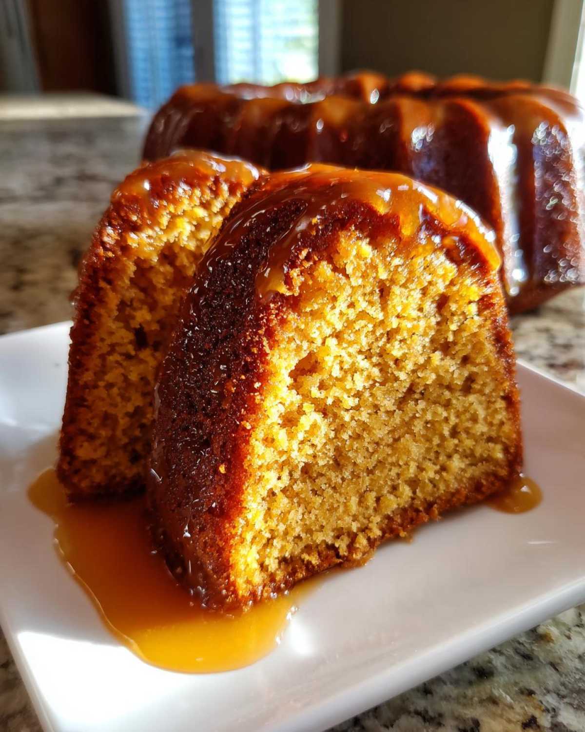 Close-up of two slices of moist Bacardi Rum Cake covered in a rich, amber glaze on a white plate.