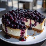 A rich, creamy blueberry cheesecake with a thick layer of blueberry topping, served on a white plate.
