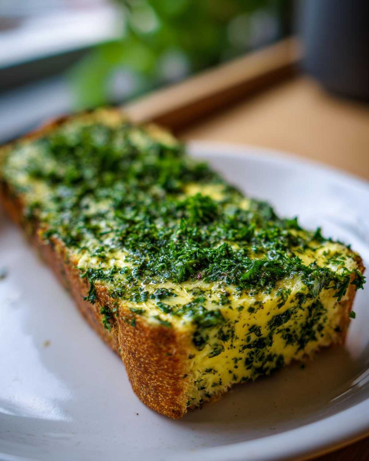 Close-up of thick-cut bread generously coated in yellow garlic butter and topped with fresh chopped parsley.