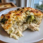 A close-up of a serving of creamy chicken broccoli rice casserole with a golden, cheesy top.