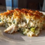 A close-up serving of creamy chicken broccoli rice casserole with a golden brown, crispy topping.