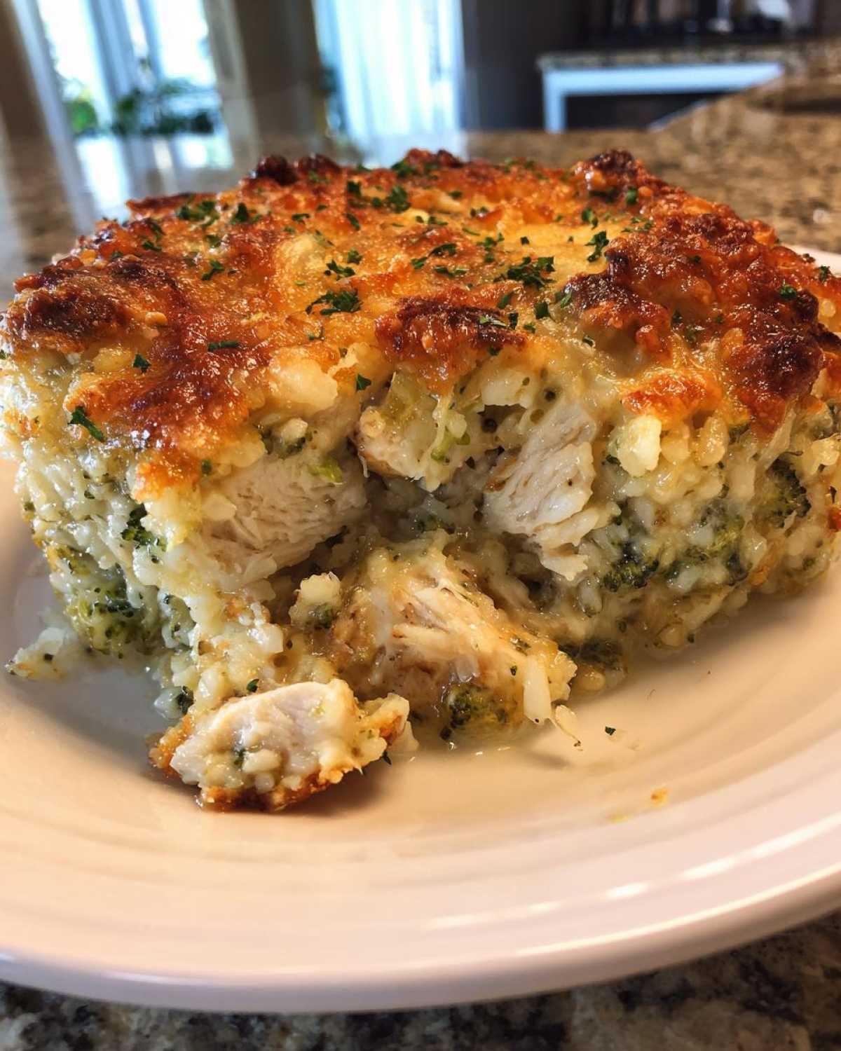 A close-up serving of creamy chicken broccoli rice casserole with a golden, cheesy, baked crust.