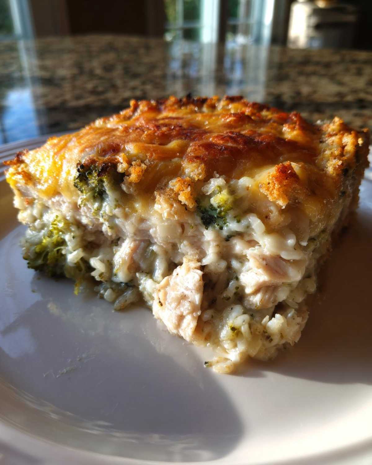 A generous serving of creamy chicken broccoli rice casserole with a golden, cheesy, and slightly crispy topping.