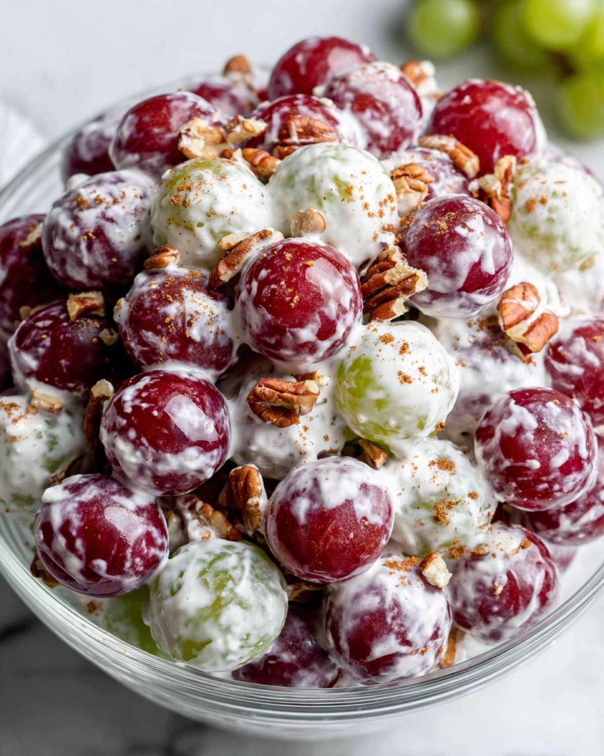 Close-up of creamy grape salad, similar to chicken salad chick grape salad, mixed with pecans and sprinkled with cinnamon.