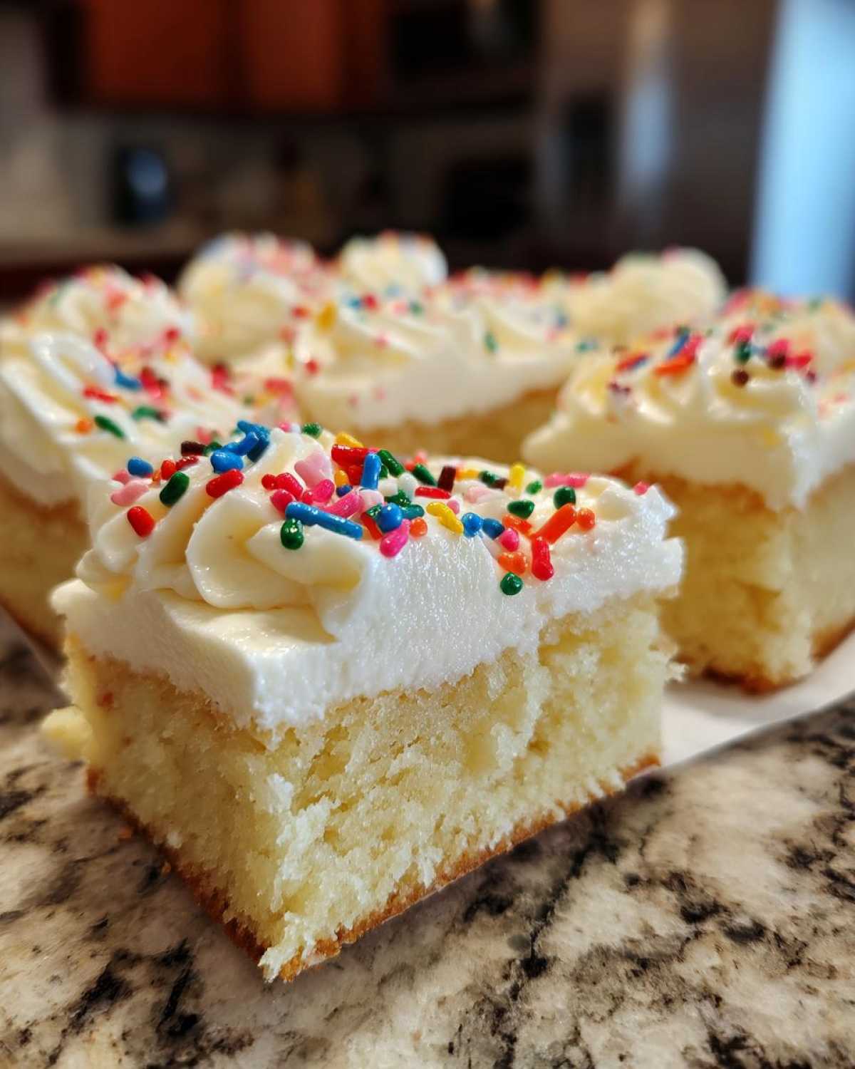 A close-up of a square slice of christmas sugar cookie bars topped with white frosting and colorful sprinkles.