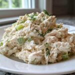 A generous serving of creamy cottage cheese chicken salad with visible celery chunks, garnished with fresh dill.